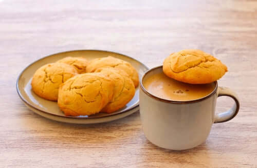 Plate of peanut butter cookies next to a cup of coffee, showcasing a cozy snack setting.